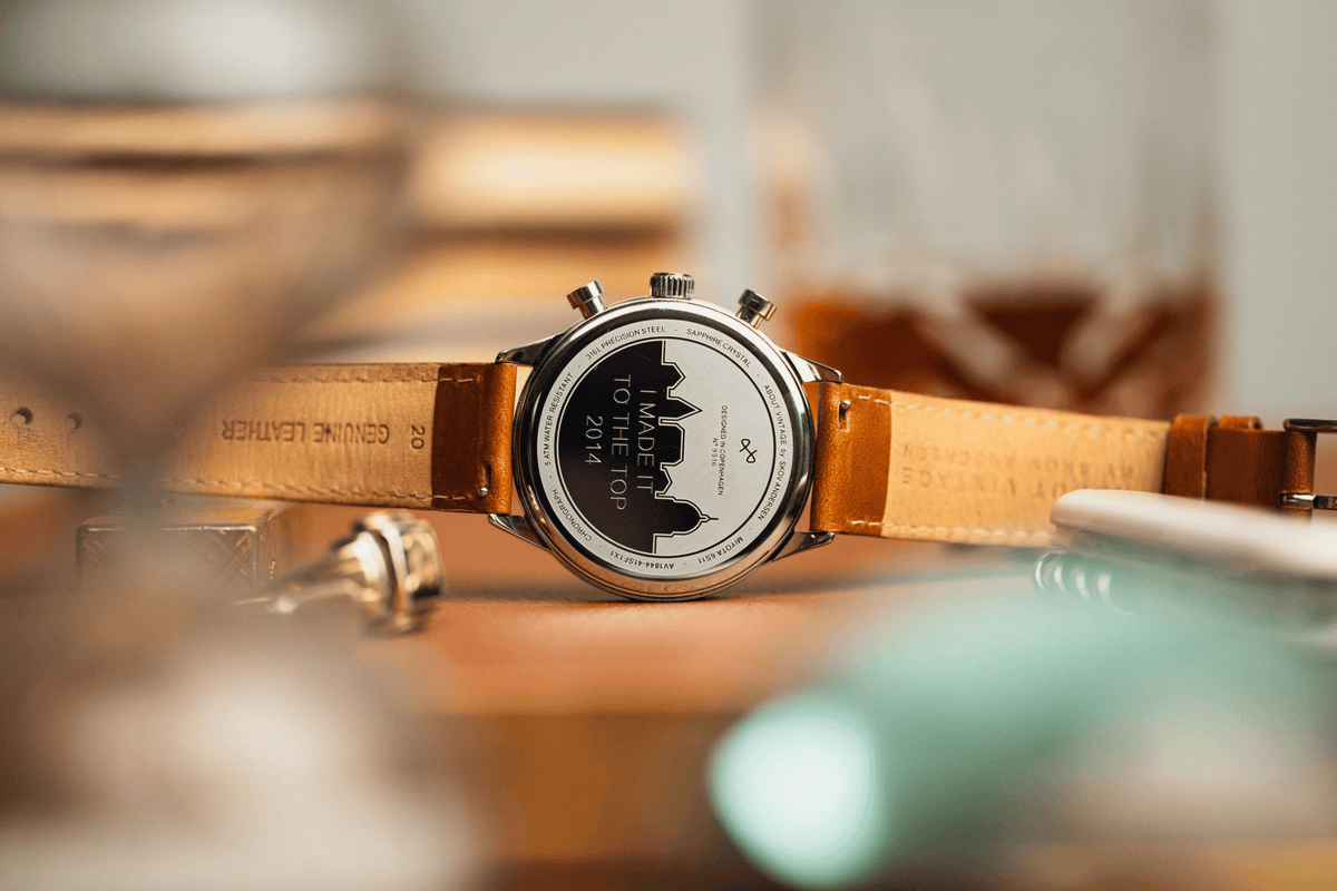 1844 Chronograph by AV86 showcasing engraved case back, polished steel, and genuine leather strap in a warm ambient setting