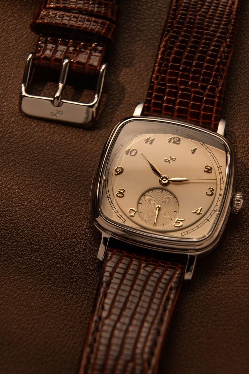1954 Amalfi Mechanical, Steel / Off White watch by AV86 with vintage-inspired dial and brown leather strap on brown background