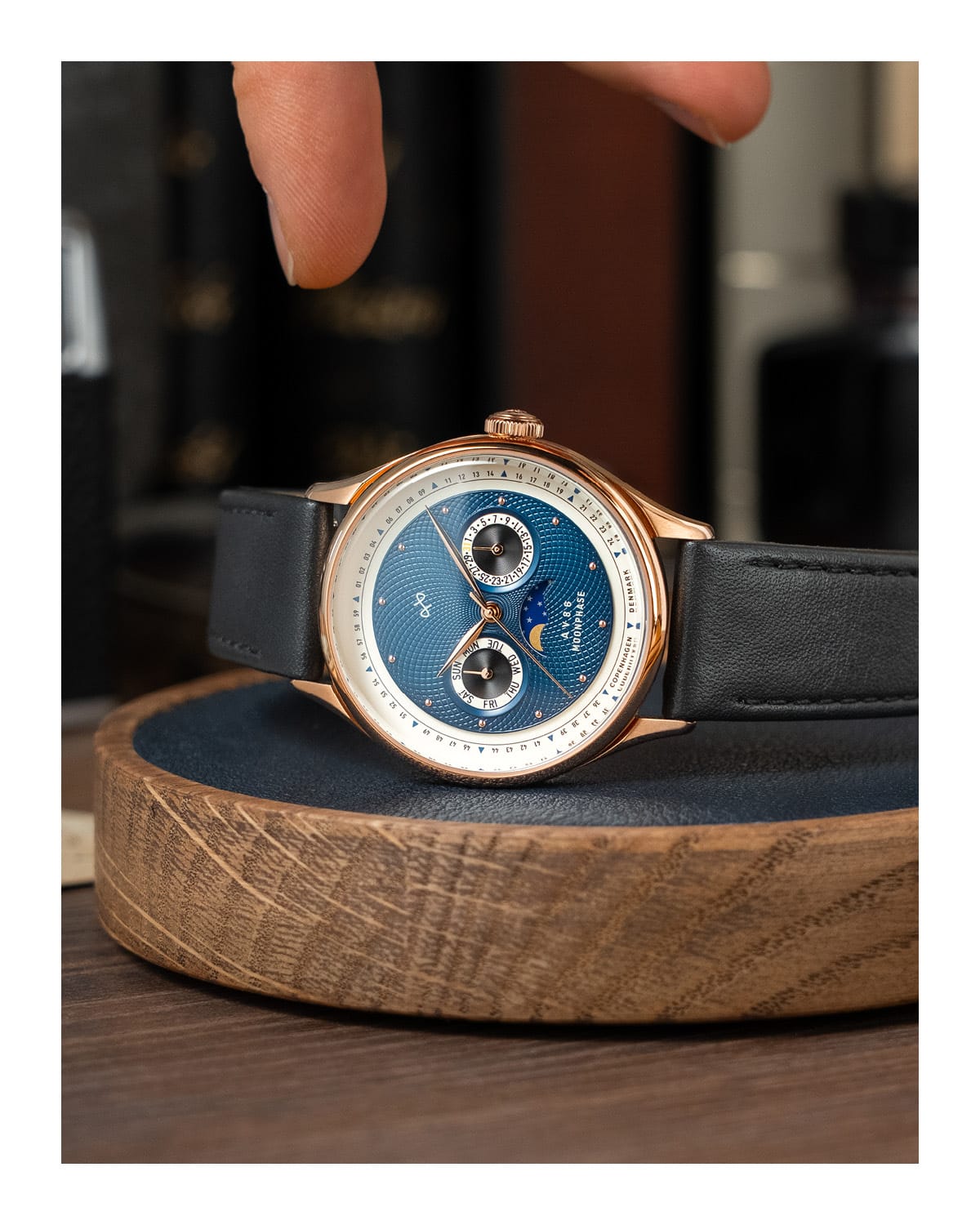 AV86 luxury moonphase watch with vintage-inspired dial, sapphire crystal, rose gold case, and black leather strap on wooden surface