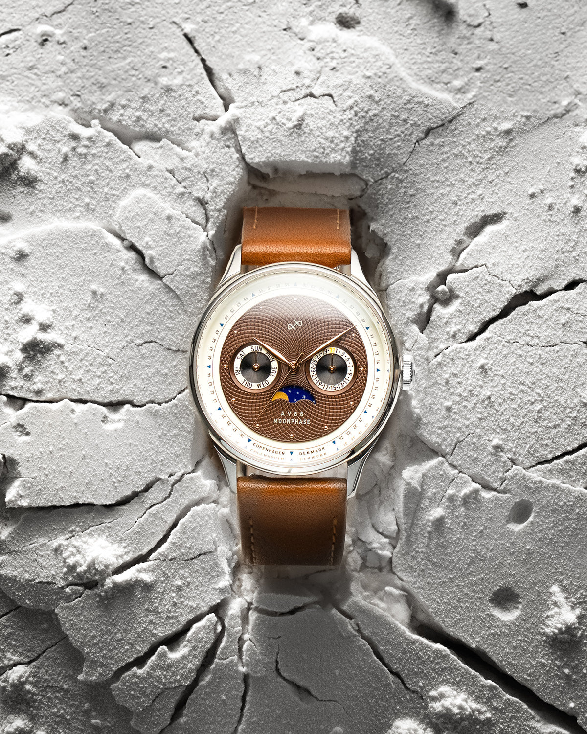 AV86 vintage-inspired Moonphase watch with textured dial, sapphire crystal, and brown leather strap on cracked surface backdrop