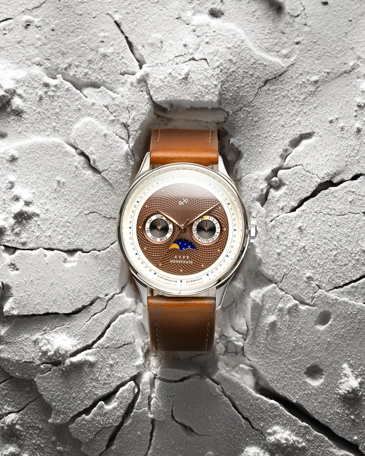 AV86 vintage-inspired Moonphase watch with textured dial, sapphire crystal, and brown leather strap on cracked surface backdrop