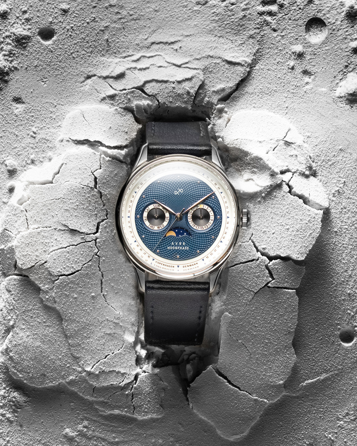 AV86 moonphase watch with vintage-inspired dial, sapphire crystal, chronograph subdials, and black leather strap on textured surface