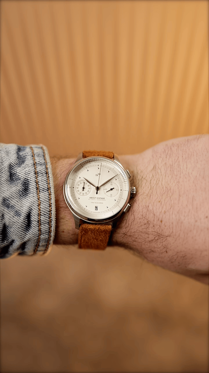 AV86 vintage-inspired chronograph with cream dial, polished case and textured brown leather strap worn with denim against warm wood tones