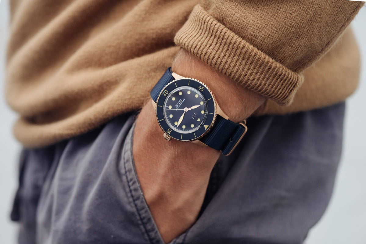 AV86 diver watch with blue dial, luminous markers, rotating bezel, and matching strap worn with a textured sweater and trousers