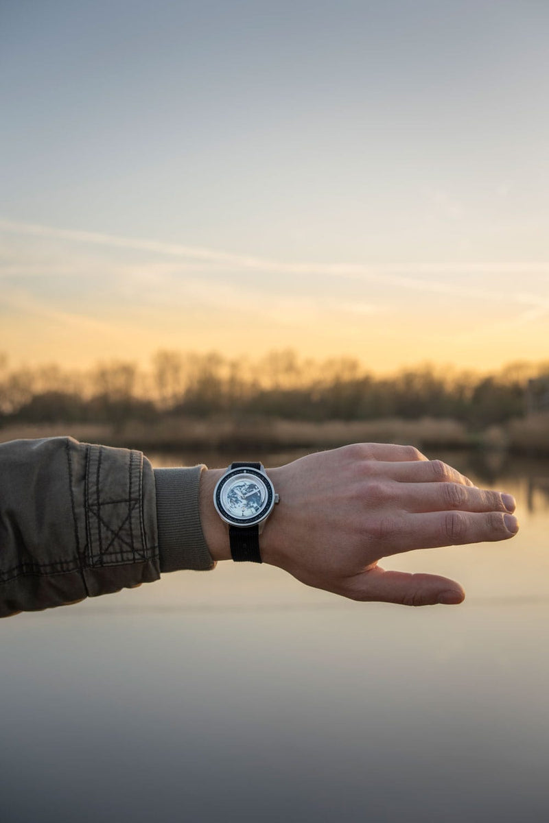 Partenariat Earthrise WWF, modèle Automatic / Édition 2025 par AV86, avec mouvement automatique, verre saphir et bracelet en caoutchouc noir, photographié en extérieur au coucher du soleil