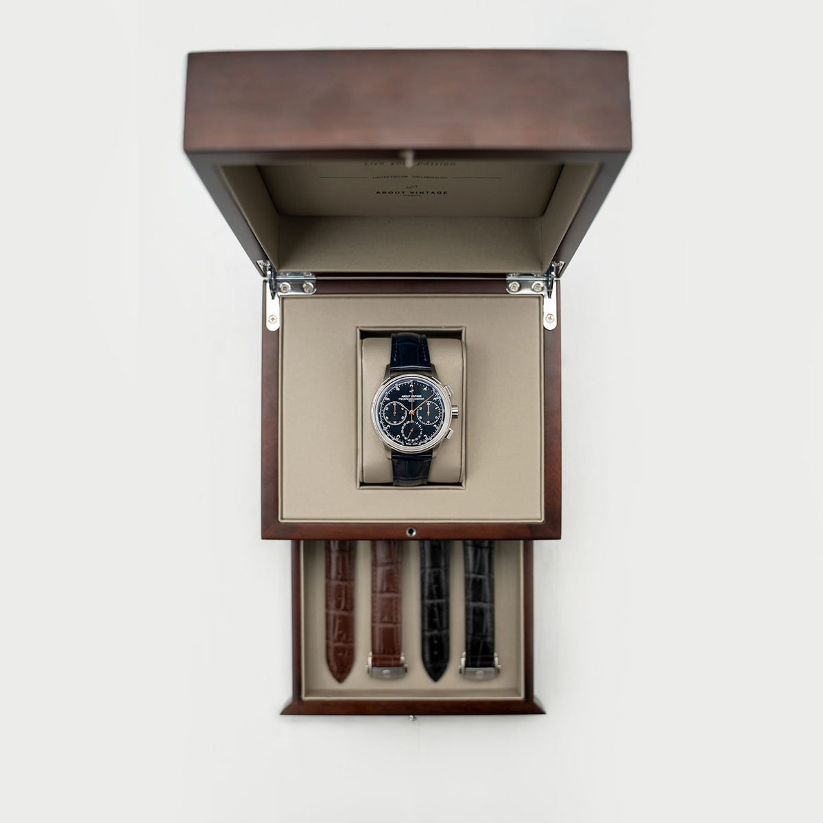 AV86 chronograph with dark dial, twin subdials, polished case, fine markers, and navy leather strap in an open wooden presentation box with spare straps
