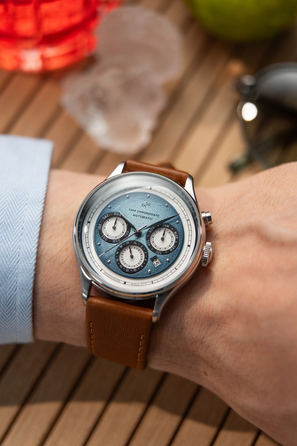1564 Chronodate Automatic by AV86 features a vintage-inspired automatic chronograph with a textured ice blue dial, sapphire crystal, and a brown leather strap, presented in a minimalist Scandinavian lifestyle setting.