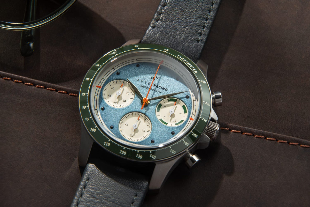 AV86 1960 Racing Chronograph, Steel / Sky Blue & Green quartz watch with blue dial, green tachymeter bezel, three subdials, and leather strap