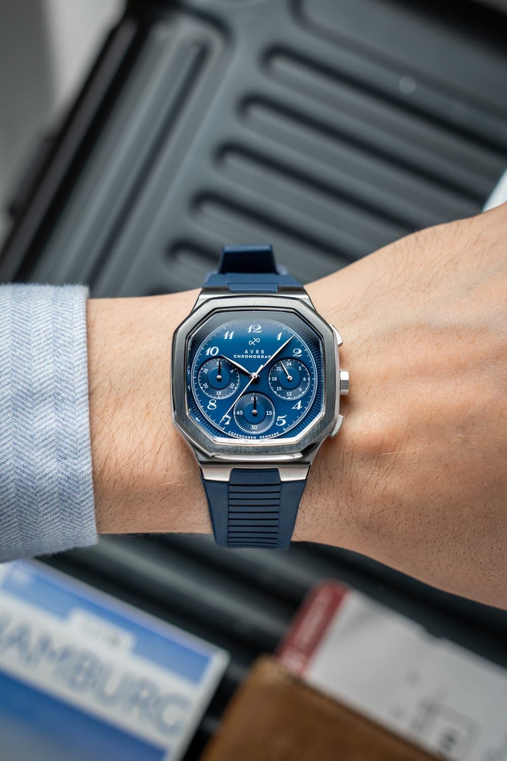 AV86製の1904 Chronograph。角張ったケース、サファイアクリスタル、ブルーの文字盤、3つのサブダイヤル、そして手首にはブルーのラバーストラップが装着されています