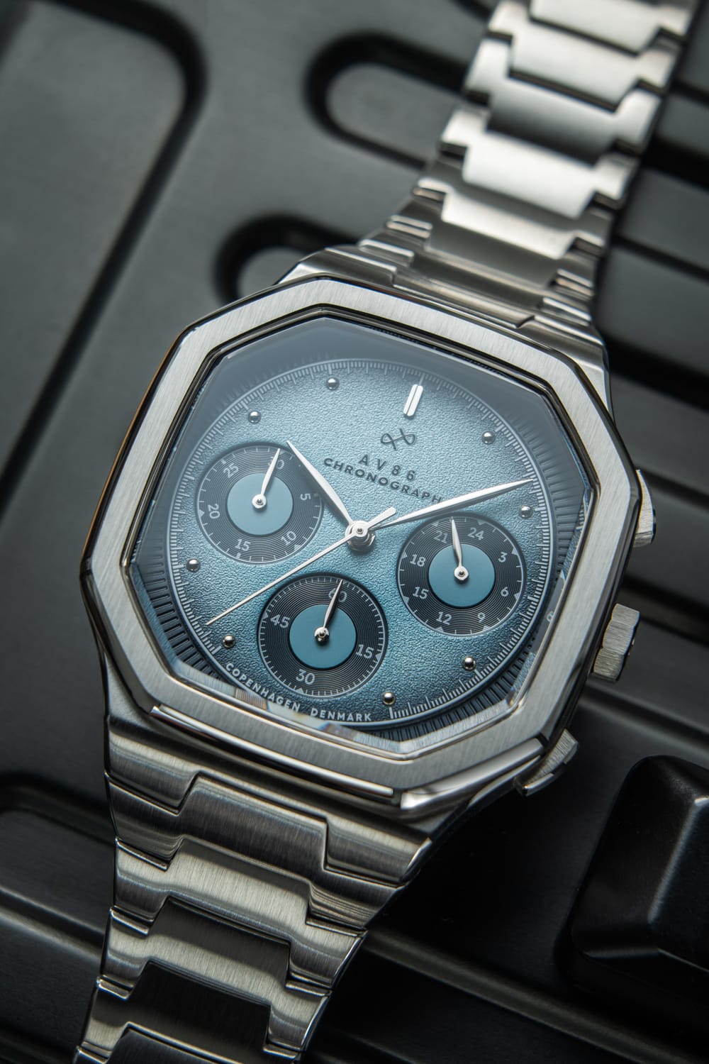 1904 Chronograph by AV86 with angular case, textured dial, sapphire crystal, chronograph subdials, and brushed steel bracelet strap