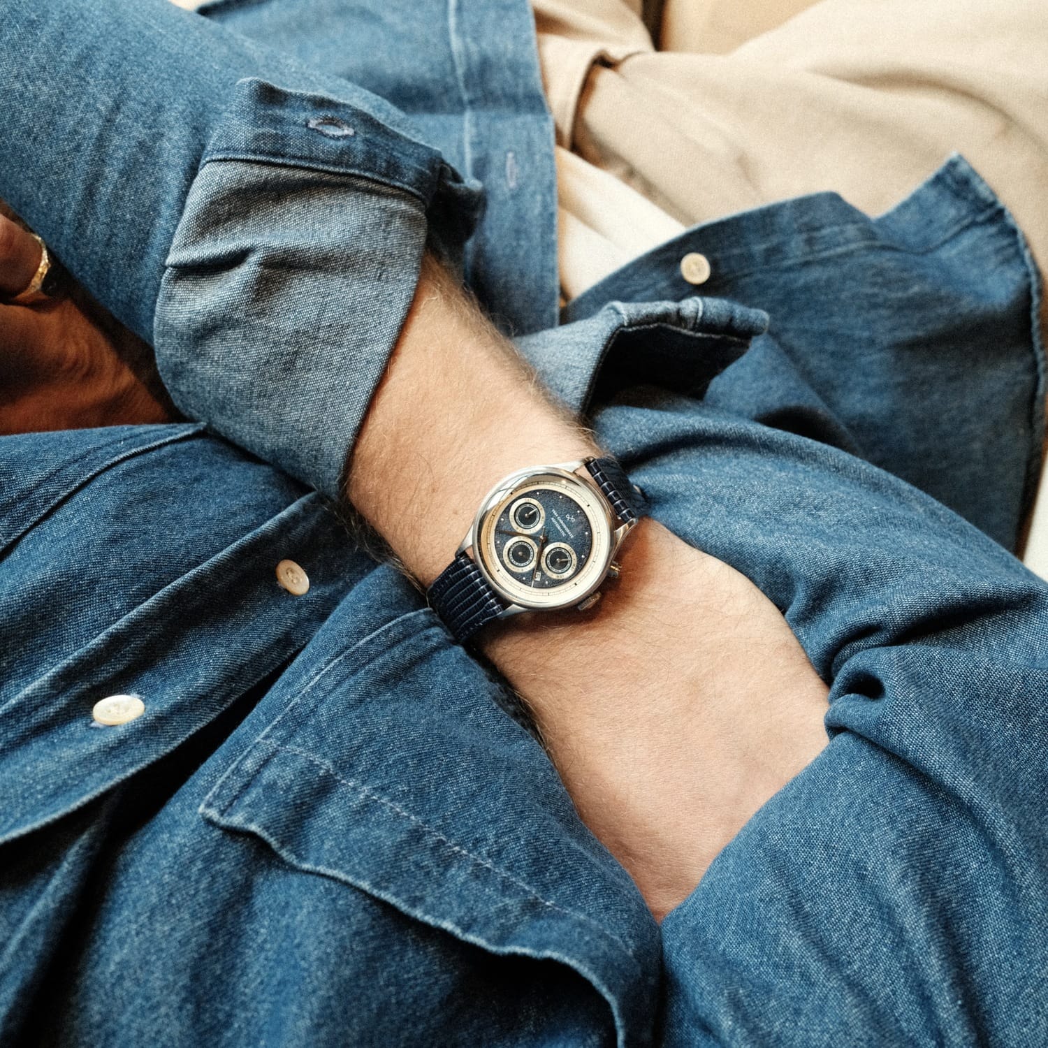1564 Chronodate Automatic by AV86 features a vintage-inspired automatic chronograph with a blue dial, three subdials, sapphire crystal, polished steel case, and a textured blue leather strap, worn casually with denim layering reflecting refined Scandinavian design and Nordic minimalism.