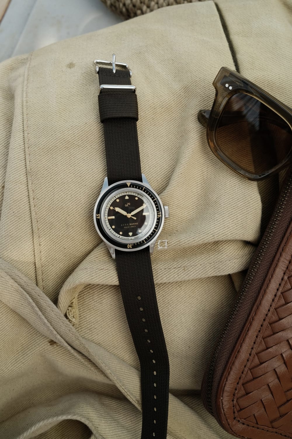 1956 Marine von AV86: Vintage-inspirierte Taucheruhr mit Saphirglas, Kompass-Lünette und schwarzem Stoffarmband auf beigem Stoffhintergrund