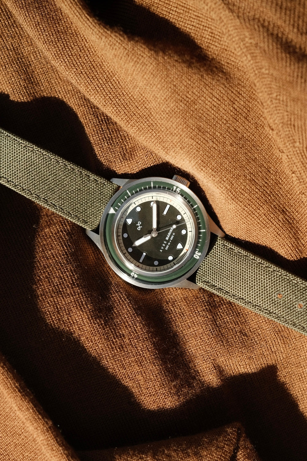 1956 Marine by AV86 vintage-inspired diver with sapphire crystal, unidirectional bezel, and durable fabric strap on textured fabric background
