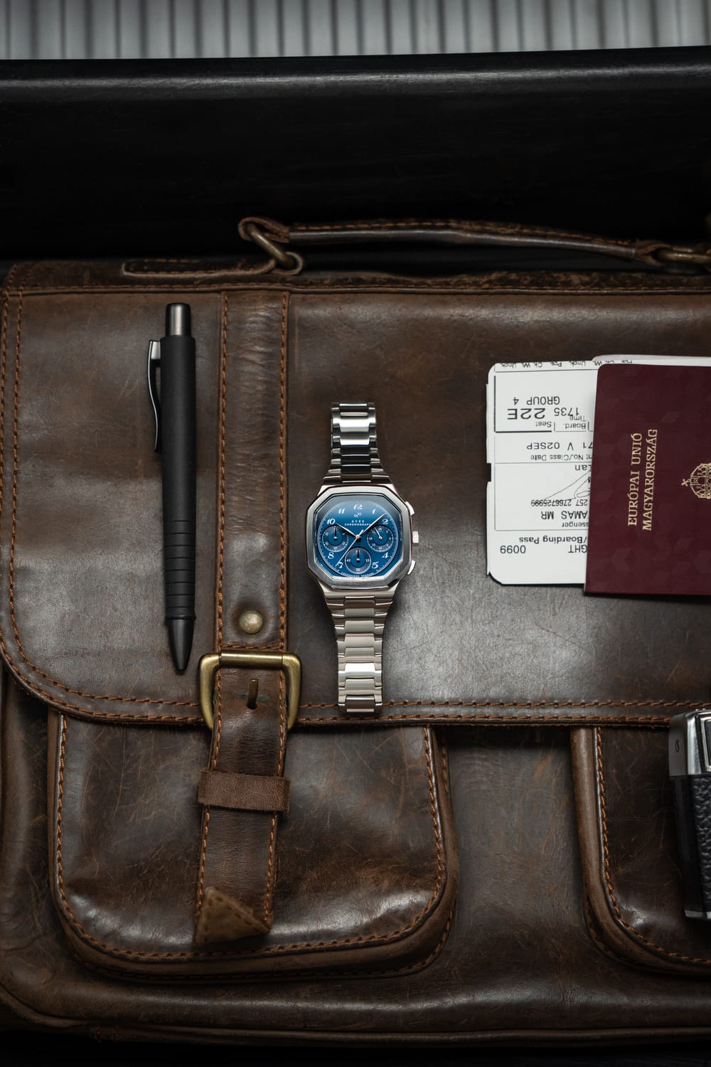 AV86製1904 Chronograph。角張ったケース、サファイアクリスタル、クロノグラフ文字盤、ブラッシュ仕上げのメタルブレスレットを備え、レザーの収納袋付き
