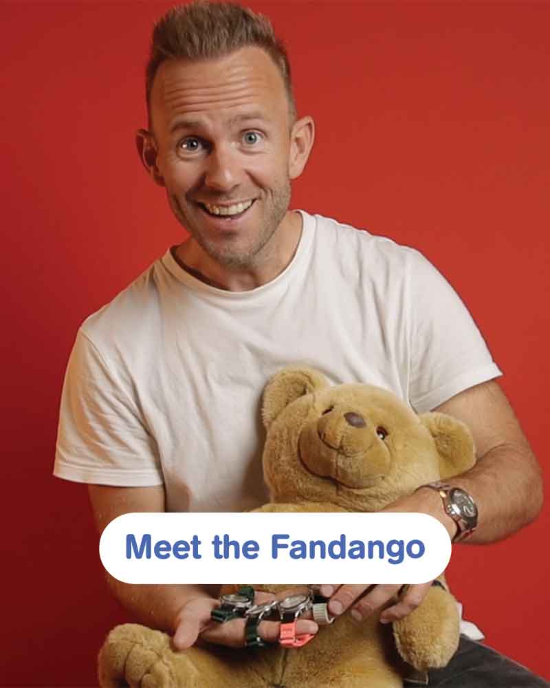 Smiling man in a white shirt holding a teddy bear against a vivid red background, with a rounded Meet the Fandango label