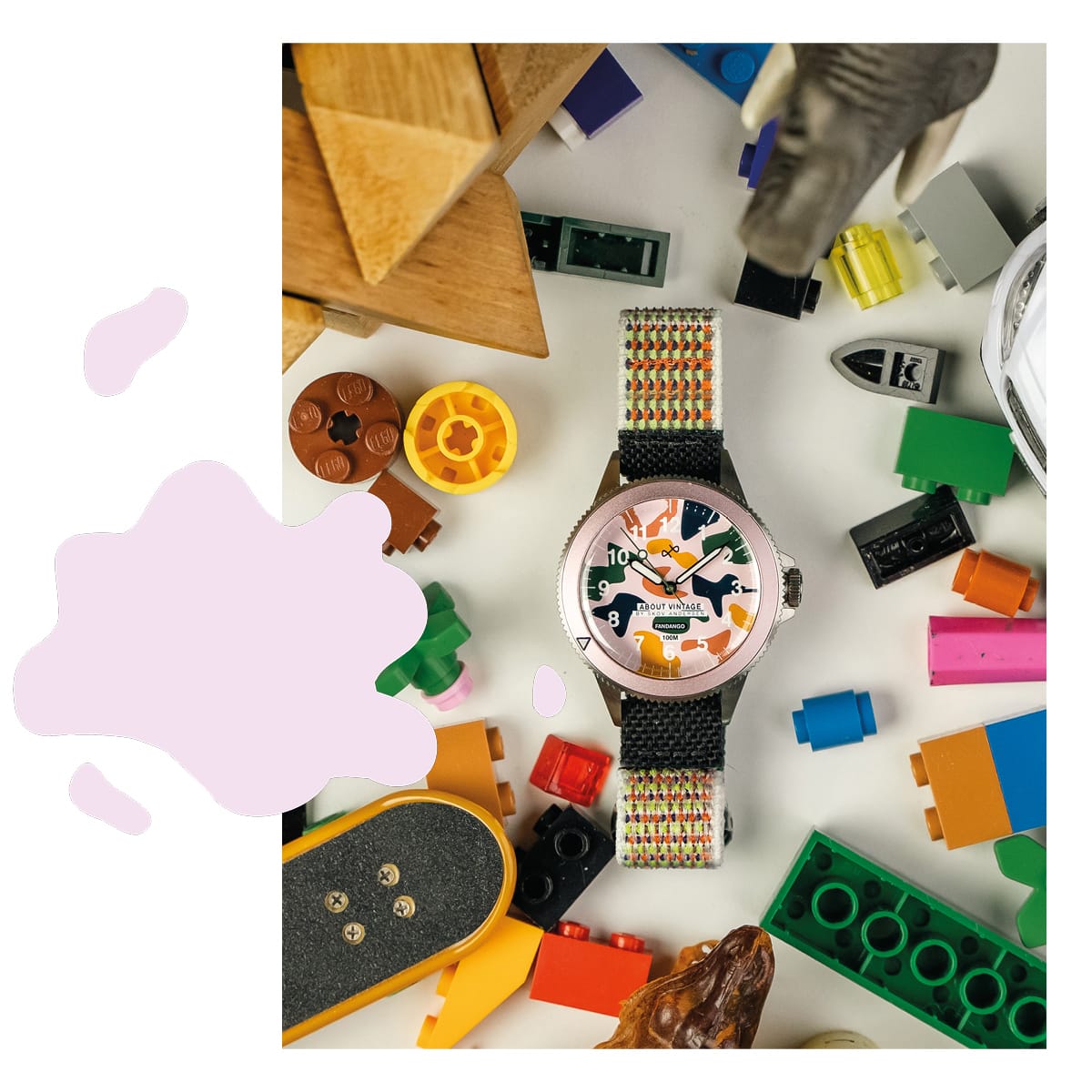 AV86 analog wristwatch with luminous numerals and black woven strap arranged among colorful craft objects on a creative workspace surface