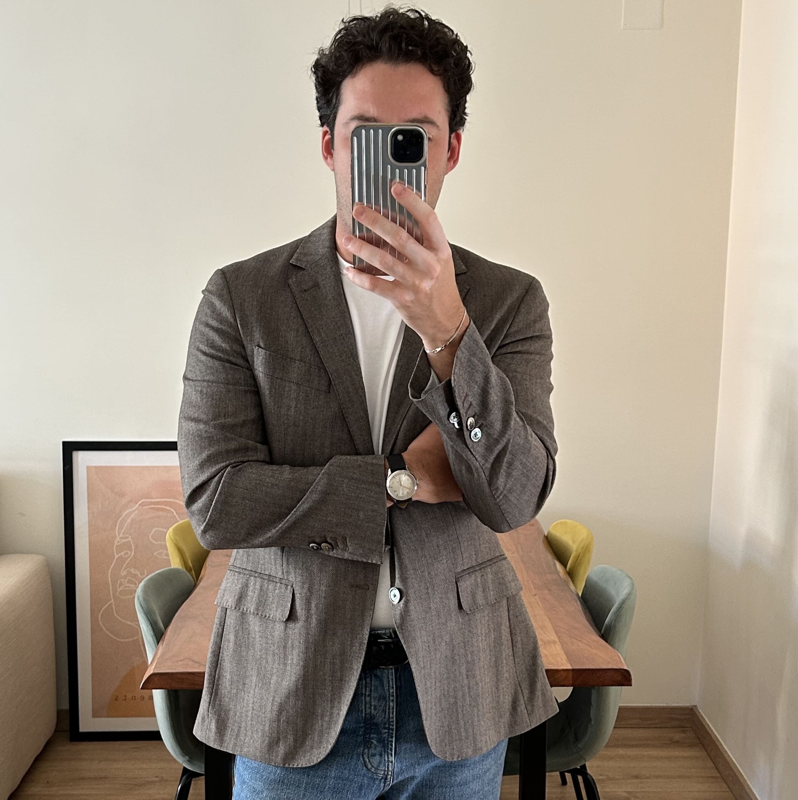 Minimalist modern Scandinavian interior with wooden table, pastel chairs, framed abstract art, and casually dressed man wearing classic watch