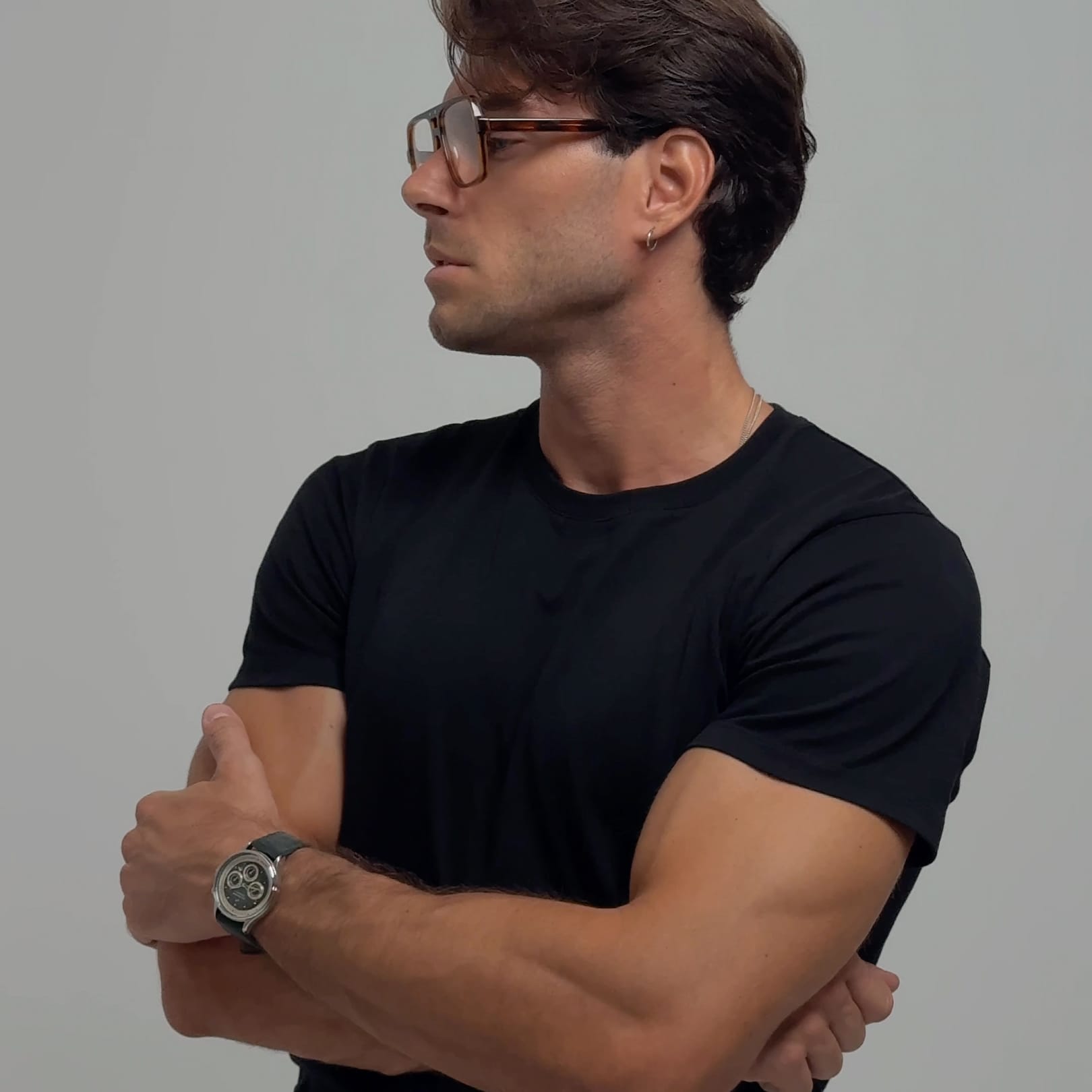 Contemporary lifestyle portrait of a man in minimalist black attire wearing a vintage-inspired AV86 chronograph with leather strap and sapphire crystal