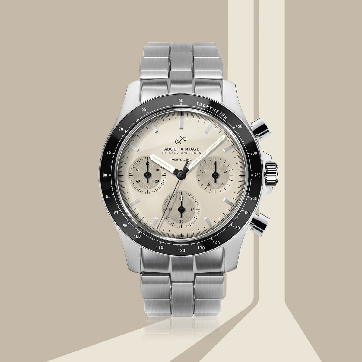 AV86 vintage-inspired chronograph with cream dial, black tachymeter bezel, three subdials, luminous markers and metal bracelet against geometric backdrop