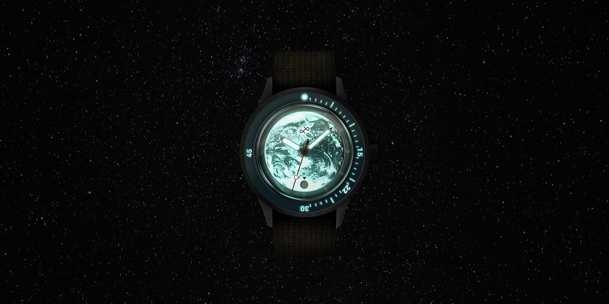 Diver watch with illuminated Earth dial, glowing markers, and black strap floating against a deep starry night sky.