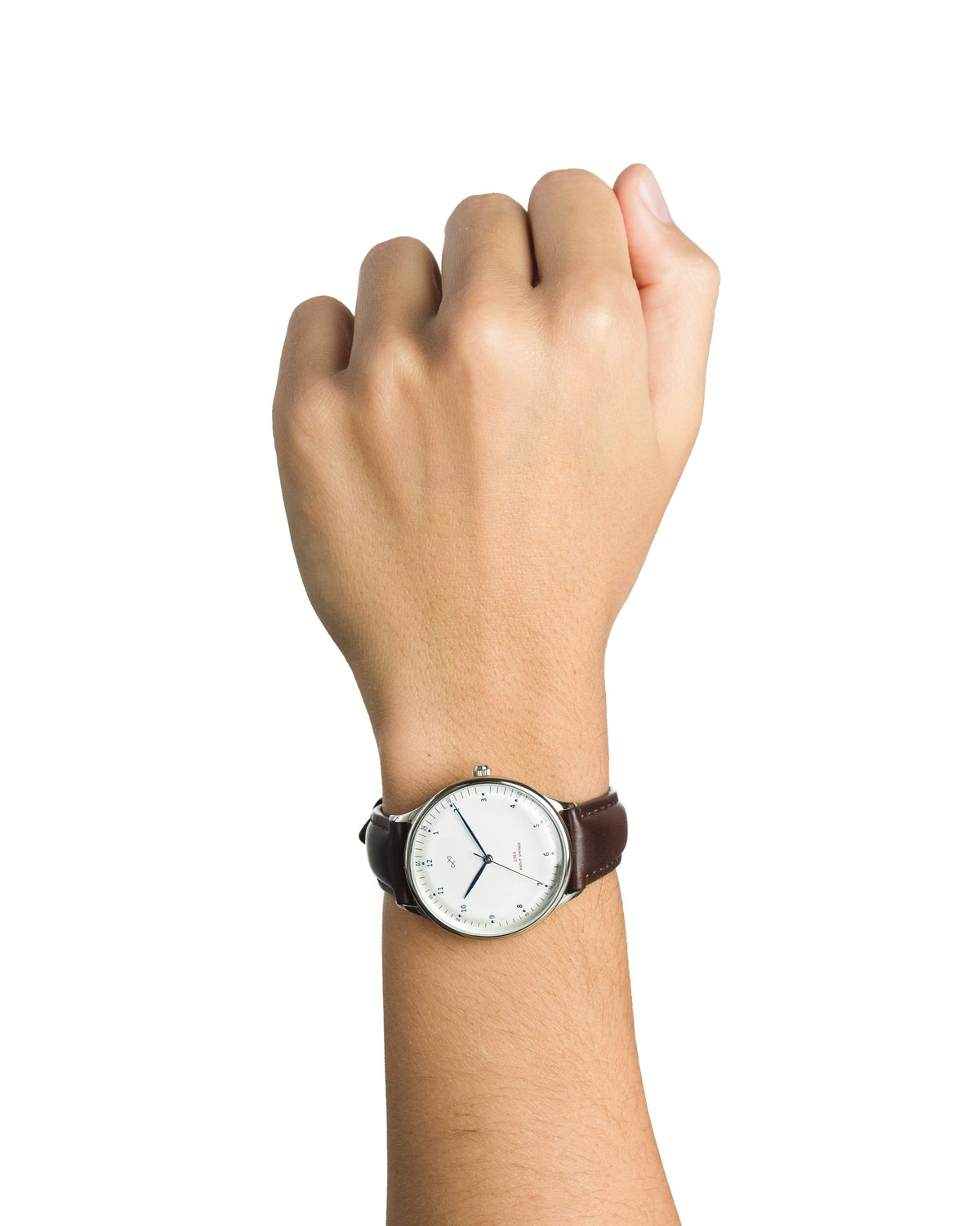 AV86 minimalist dress watch with a pale round dial and brown leather strap worn on a raised wrist against a plain backdrop