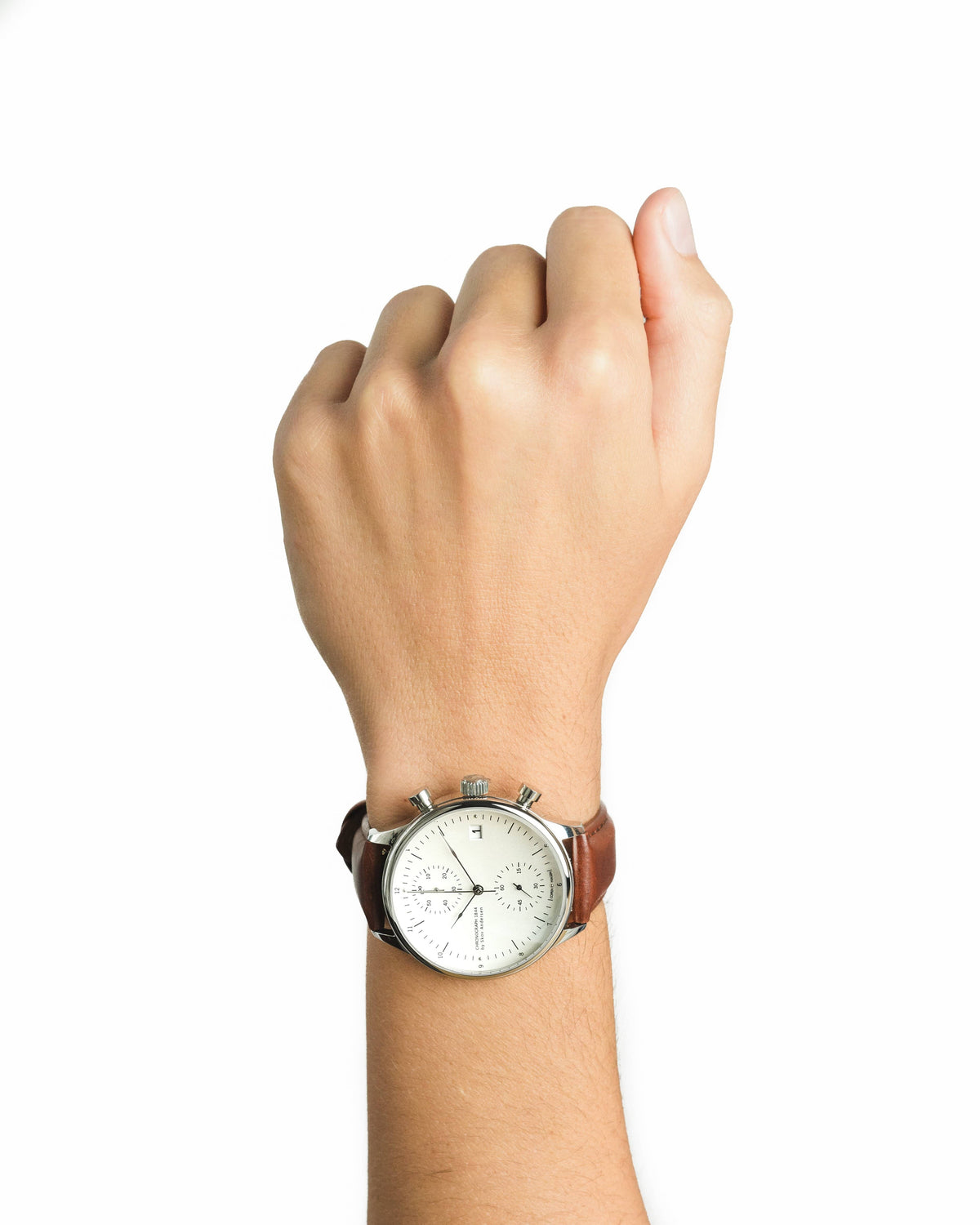AV86 vintage inspired chronograph with a pale dial and brown leather strap worn on a raised wrist against a plain backdrop
