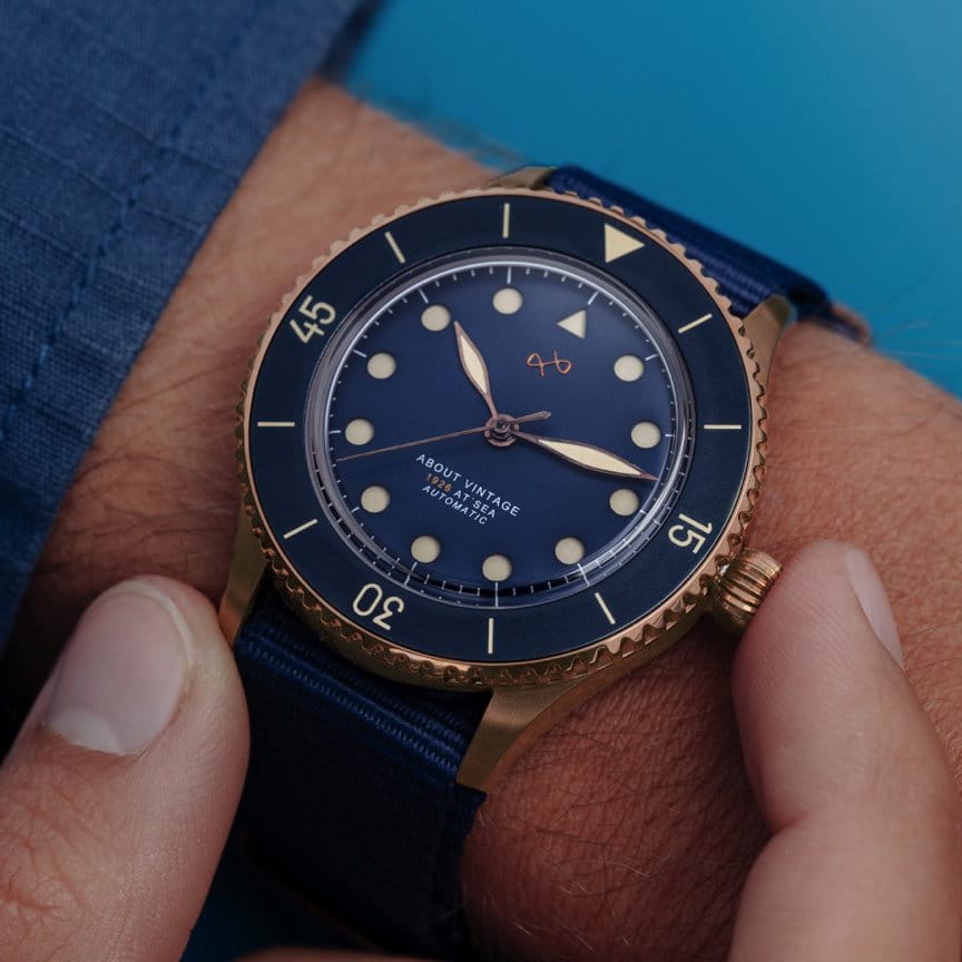 AV86 vintage-inspired diver watch with blue dial, rotating dive bezel, luminous markers, textured strap, and warm-toned metal case