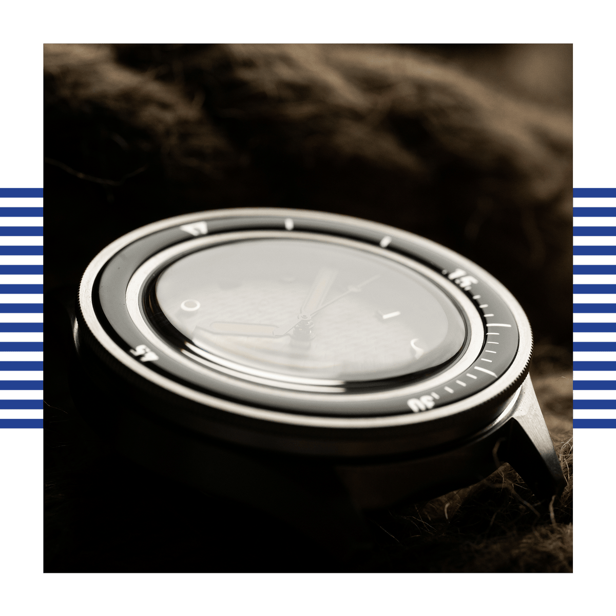 AV86 diver watch closeup with rotating bezel, minimalist dial, luminous markers, broad hands and domed crystal on a dark textured surface