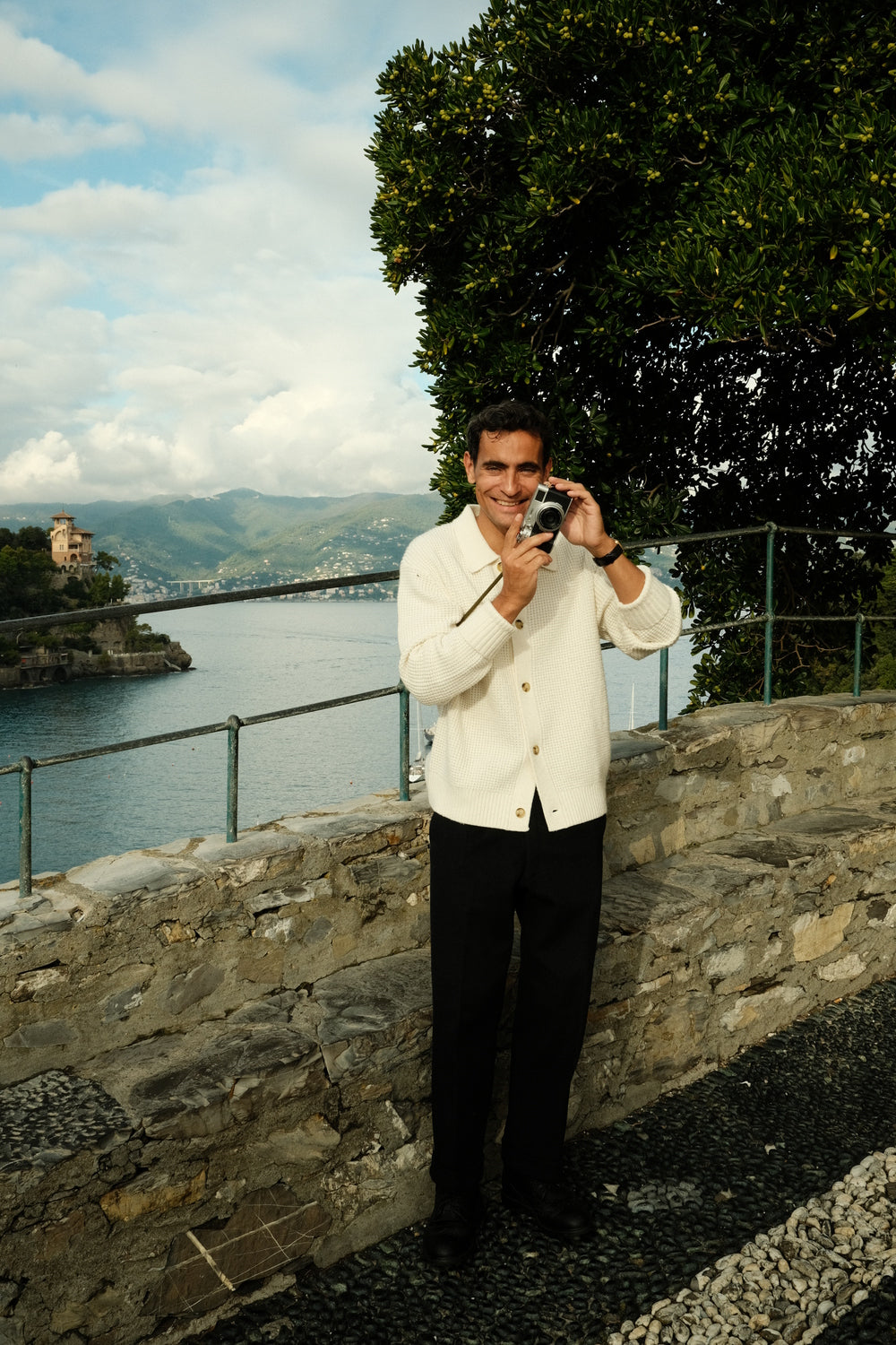 Man in elegant cream cardigan and black trousers by the sea wearing 1954 Amalfi Mechanical gold watch by AV86