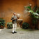 Man in casual Scandinavian outfit with 1954 Amalfi Mechanical, Gold / Midnight Blue by AV86 exploring historic Mediterranean courtyard