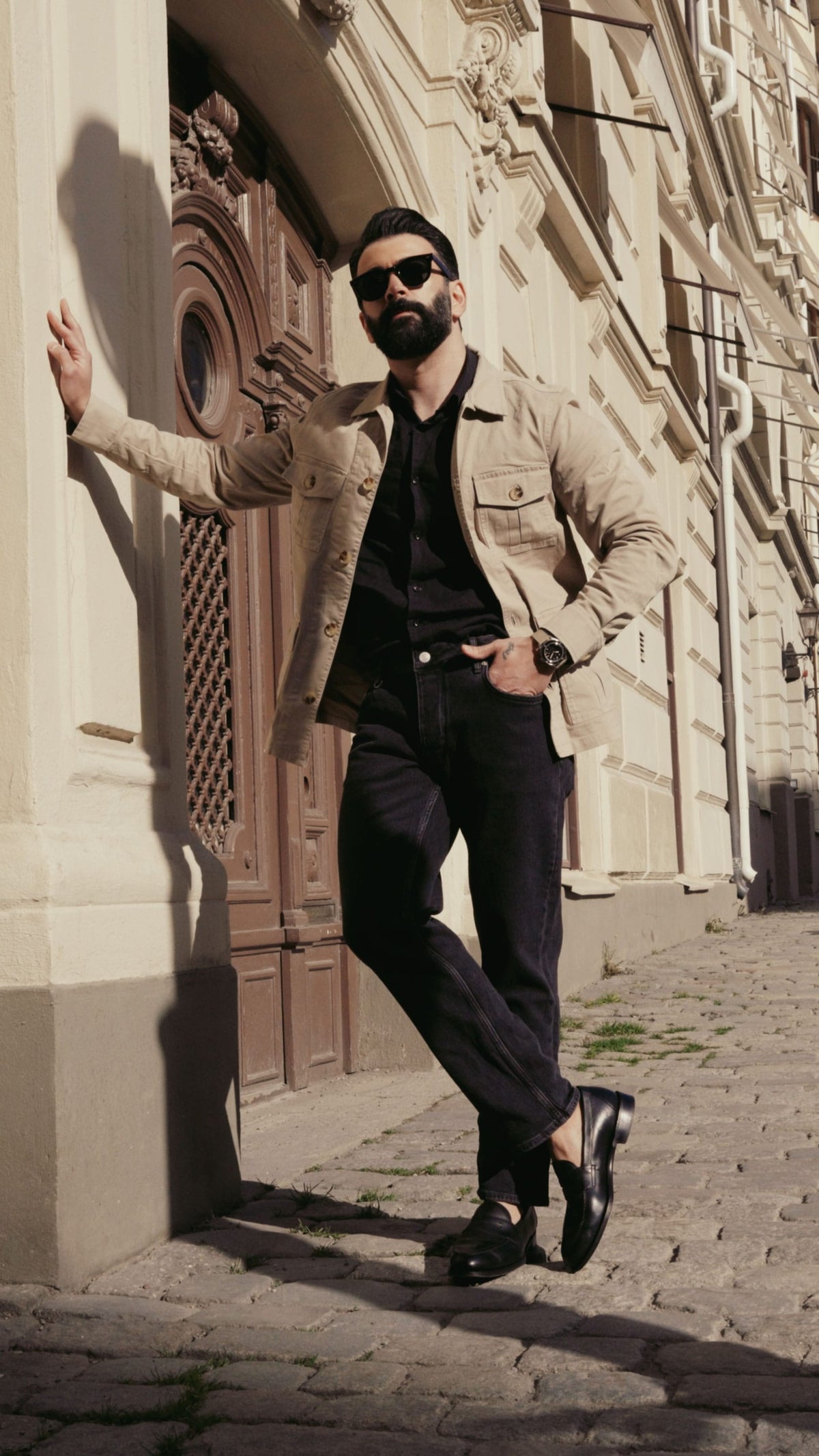AV86 watch worn with a dark casual outfit on a sunlit cobblestone street beside ornate historic architecture