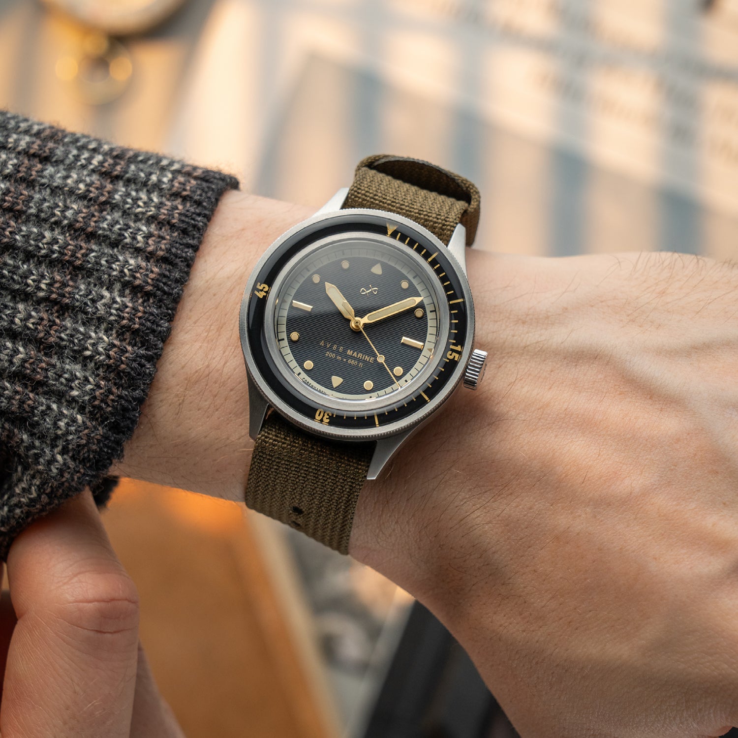 1956 Marine by AV86 vintage-inspired diver with compass bezel, sapphire crystal, and olive fabric strap on wrist