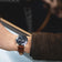 1960 Racing Chronograph by AV86 with vintage-inspired dial, sapphire crystal, and brown leather strap on wrist driving a car