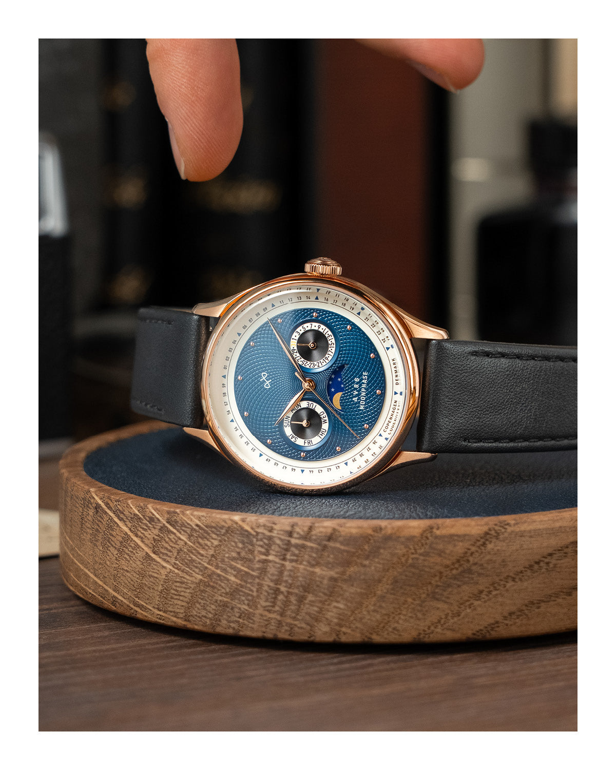 AV86 luxury moonphase watch with vintage-inspired dial, sapphire crystal, rose gold case, and black leather strap on wooden surface