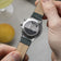 1564 Chronodate Automatic by AV86 showcasing engraved case back with cityscape motif and leather strap details