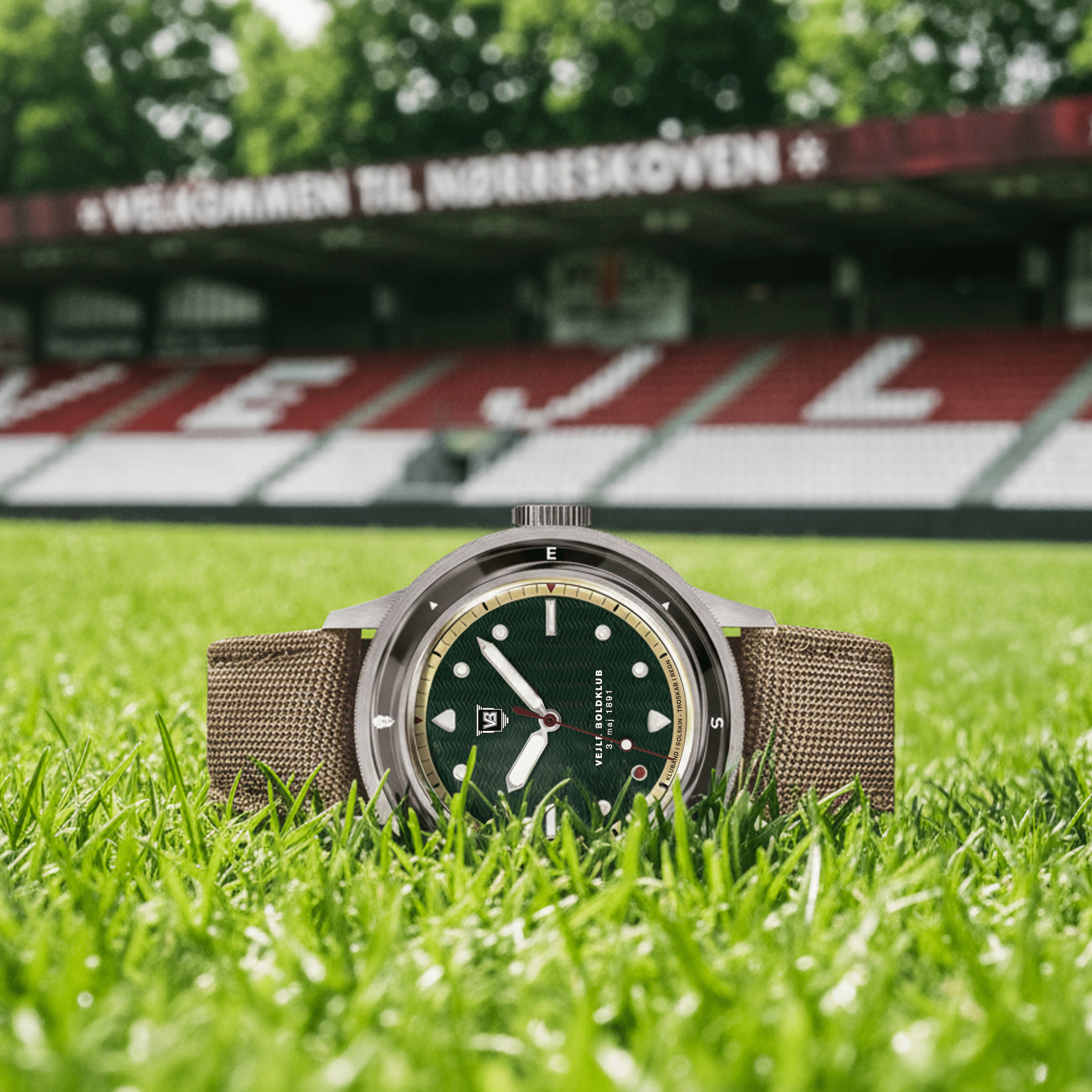 VB Kong Hans Eg, Limited Edition by AV86 vintage-inspired diver with compass bezel, sapphire crystal, and textured fabric strap on grass at stadium