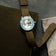 Earthrise WWF Partnership, Automatic / 2026 Edition by AV86 with a blue bezel and brown fabric strap, beside map and leather folio