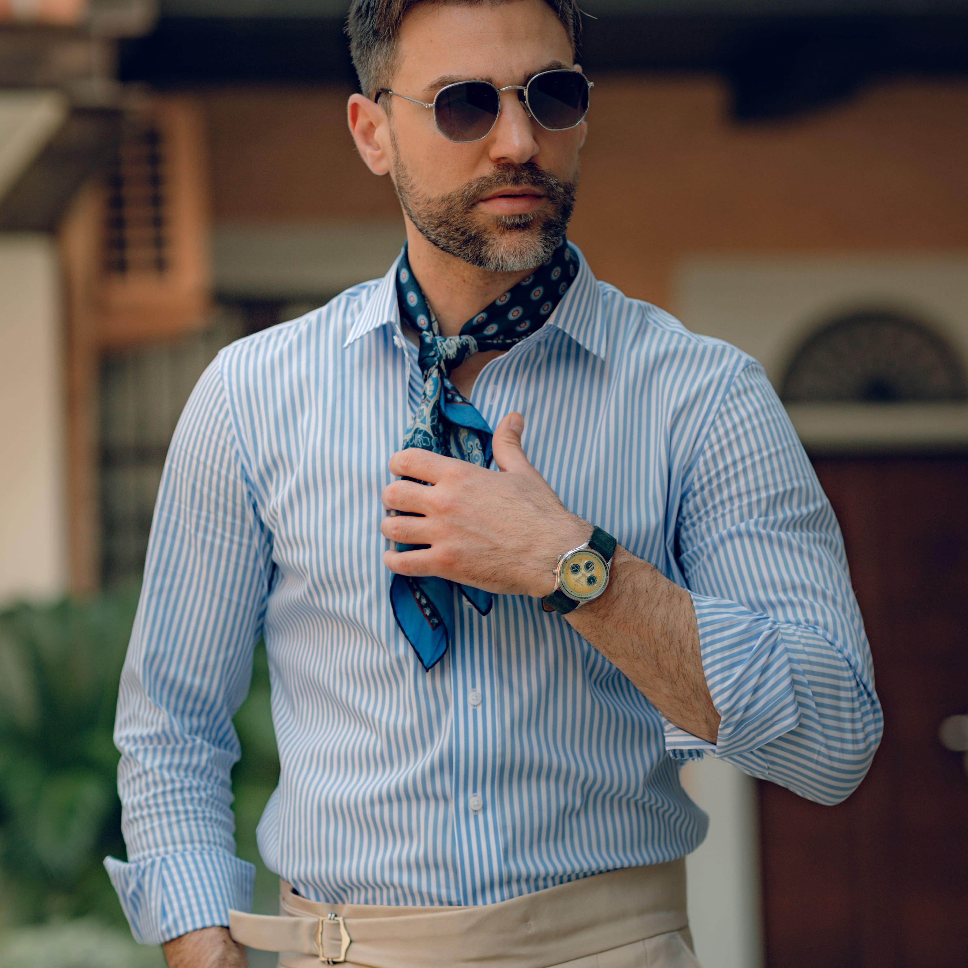Man dressed in smart casual attire with striped shirt and scarf, wearing a vintage-inspired chronograph watch by AV86 with leather strap