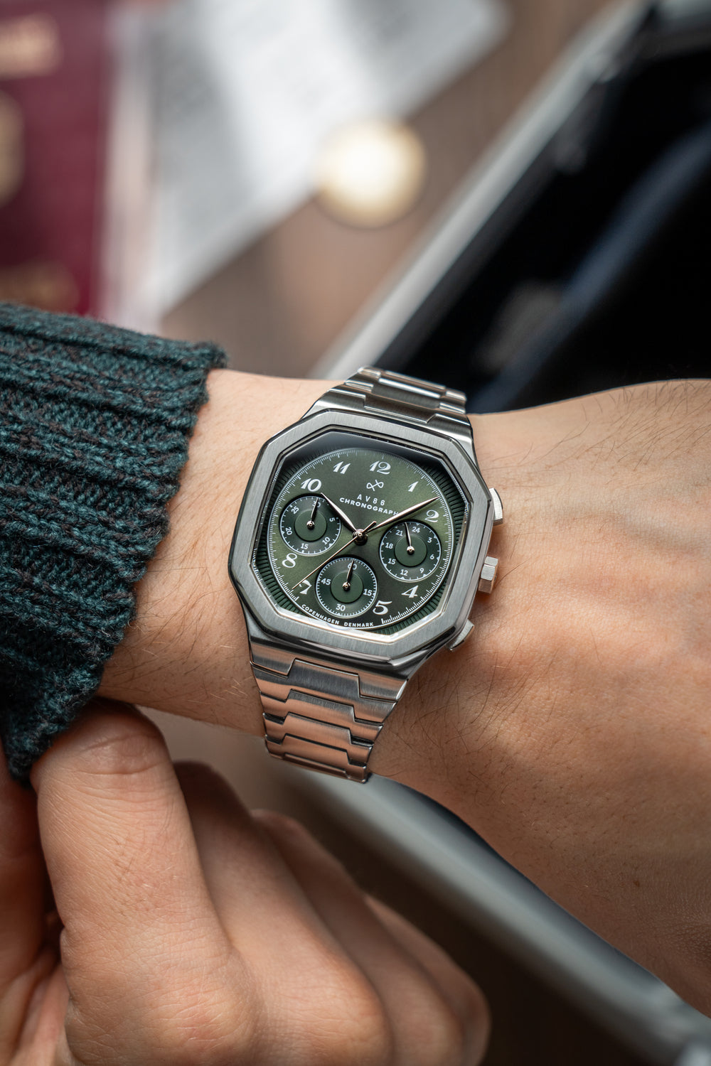 1904 Chronograph by AV86 with angular case, olive green dial, sapphire crystal, chronograph subdials, and steel link strap