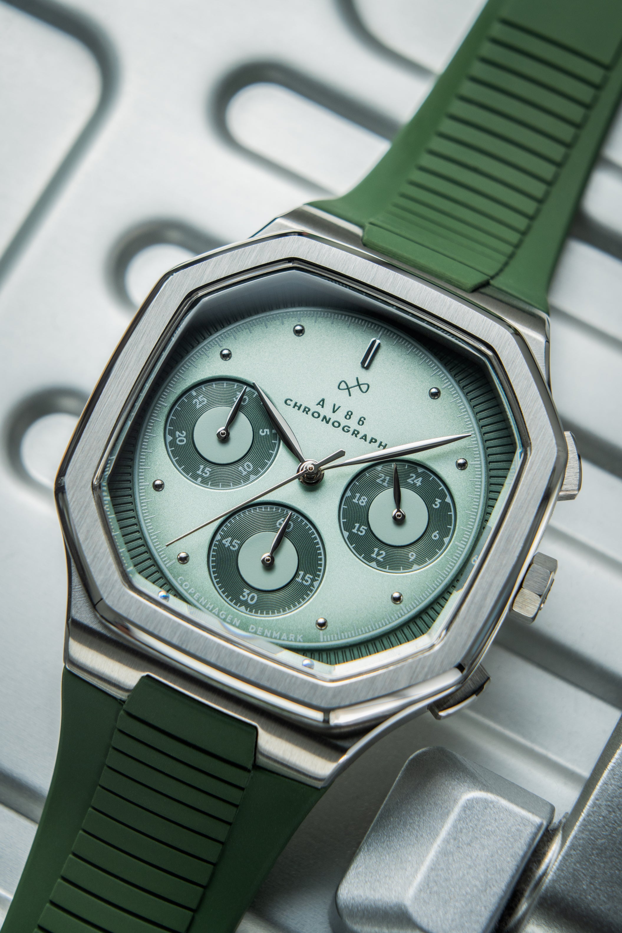 1904 Chronograph by AV86 with angular case, sapphire crystal, chronograph dial, and textured green rubber strap in minimalist style
