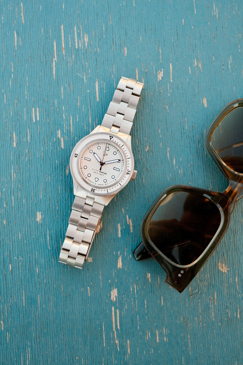 1956 Marine by AV86 vintage-inspired diver with sapphire crystal, stainless steel case, bezel, and metal bracelet strap on textured surface