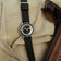 1956 Marine by AV86 vintage-inspired diver with sapphire crystal, compass bezel, and black fabric strap on beige fabric background