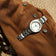1956 Marine by AV86 luxury diver watch with sapphire crystal, rotating bezel, and brushed metal bracelet on textured fabric background