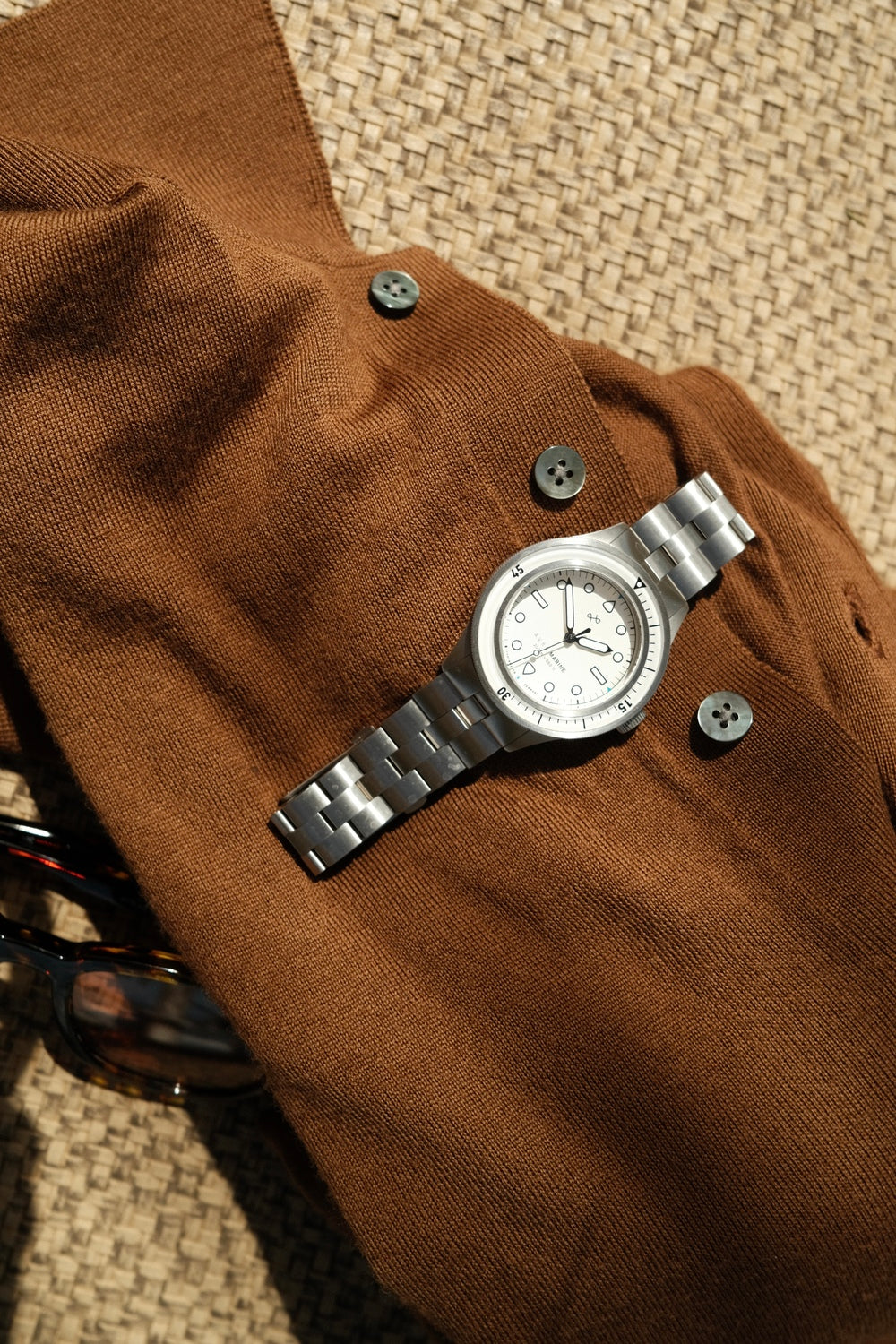 1956 Marine by AV86 luxury diver watch with sapphire crystal, rotating bezel, and brushed metal bracelet on textured fabric background