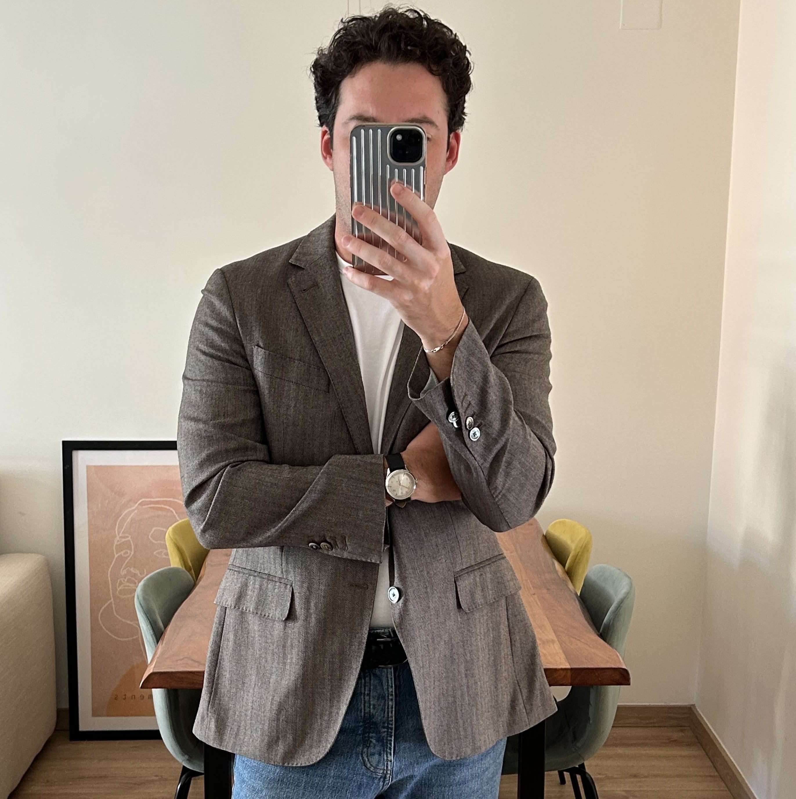 Minimalist modern Scandinavian interior with wooden table, pastel chairs, framed abstract art, and casually dressed man wearing classic watch