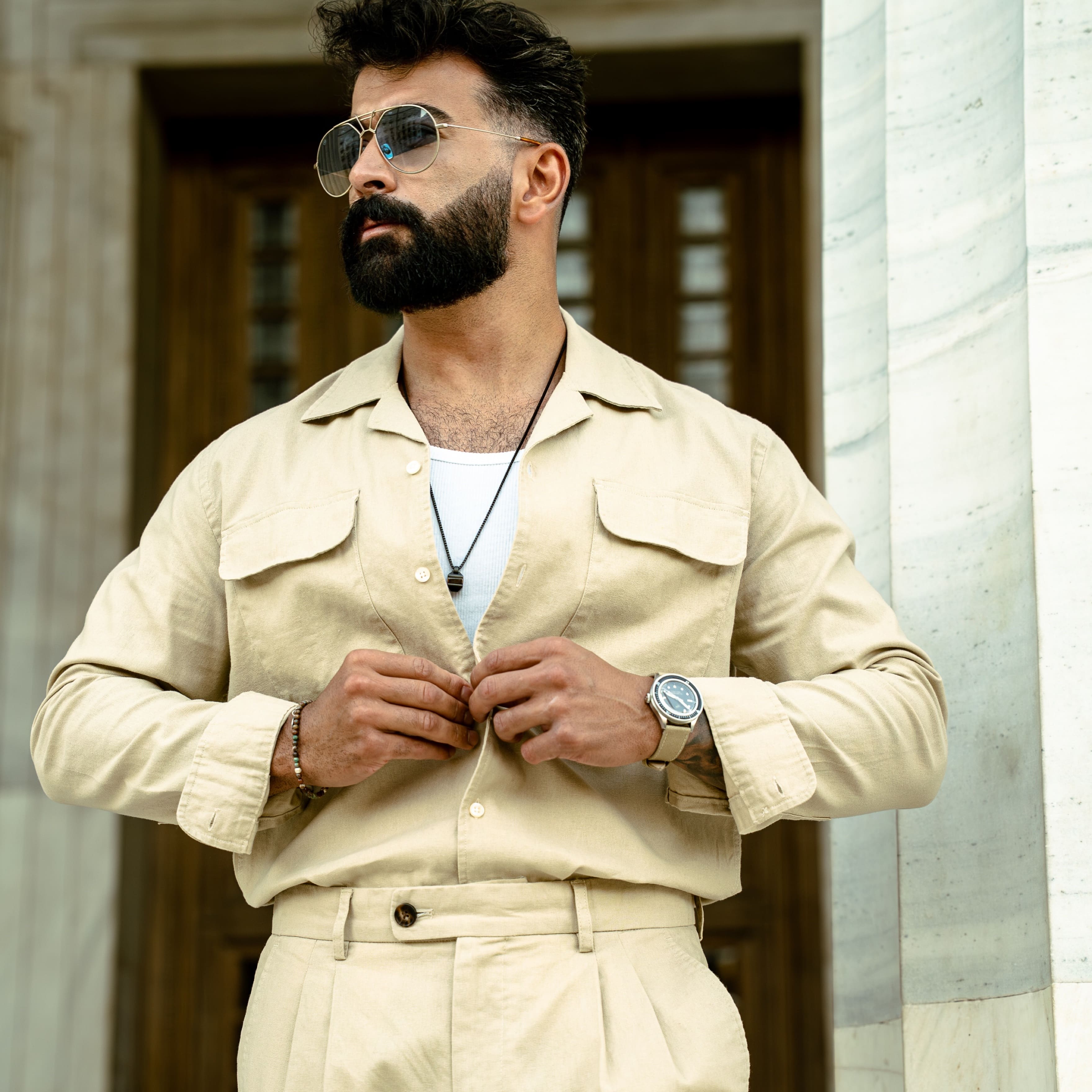 Man in beige linen outfit with aviator sunglasses wearing AV86 vintage-inspired chronograph watch with sapphire crystal and leather strap