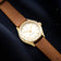 1968 Sixtyeight by AV86 vintage-inspired dress watch with sapphire crystal, gold case, and brown leather strap on dark textile background