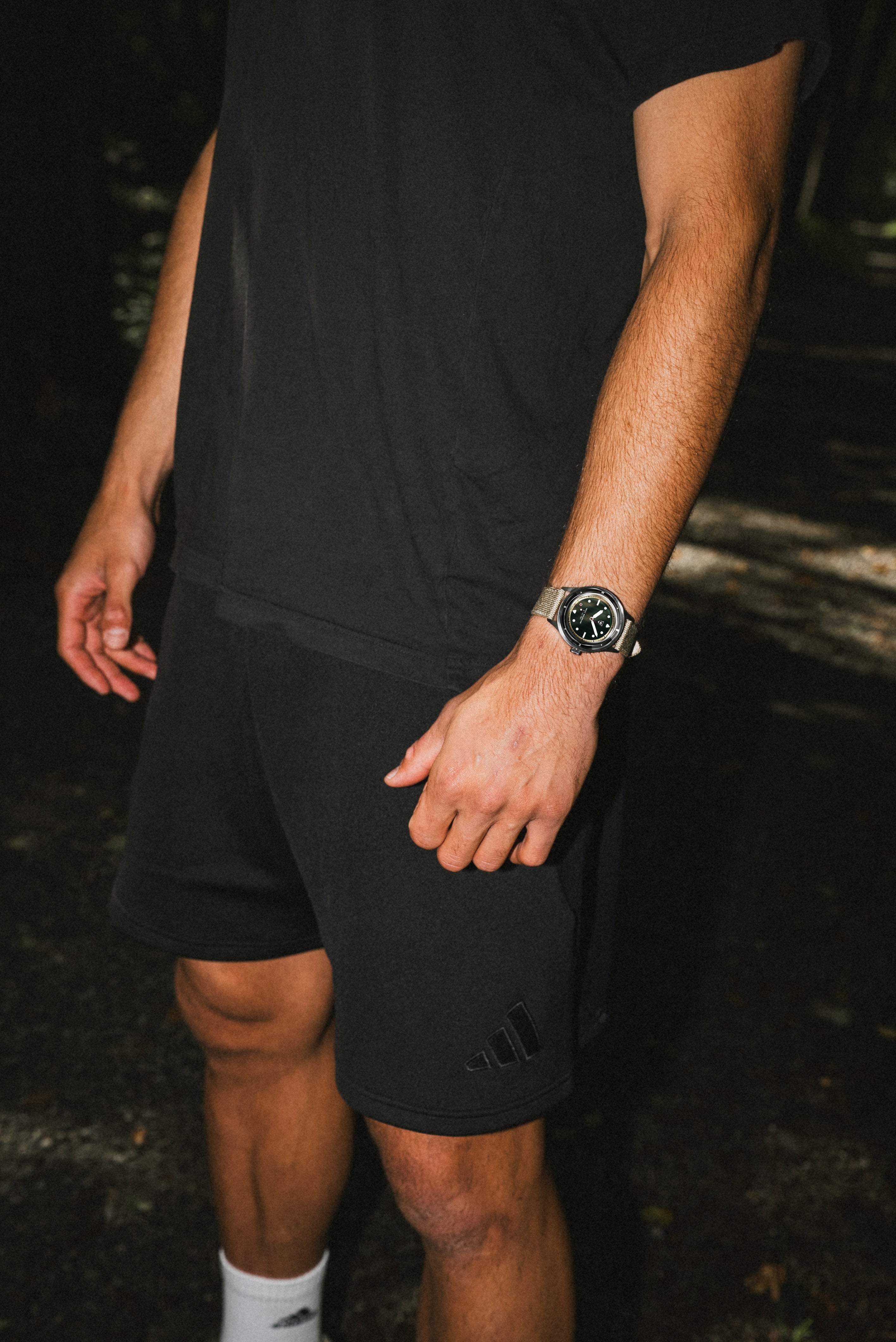 Man wearing a vintage-inspired AV86 diver watch with compass bezel and sapphire crystal in casual black sportswear outdoors